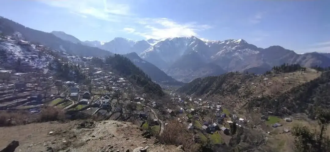 Hajitra village spread across the slopes of the Karnah valley in Kupwara, with snow peaks behind, on the road to Teetwal