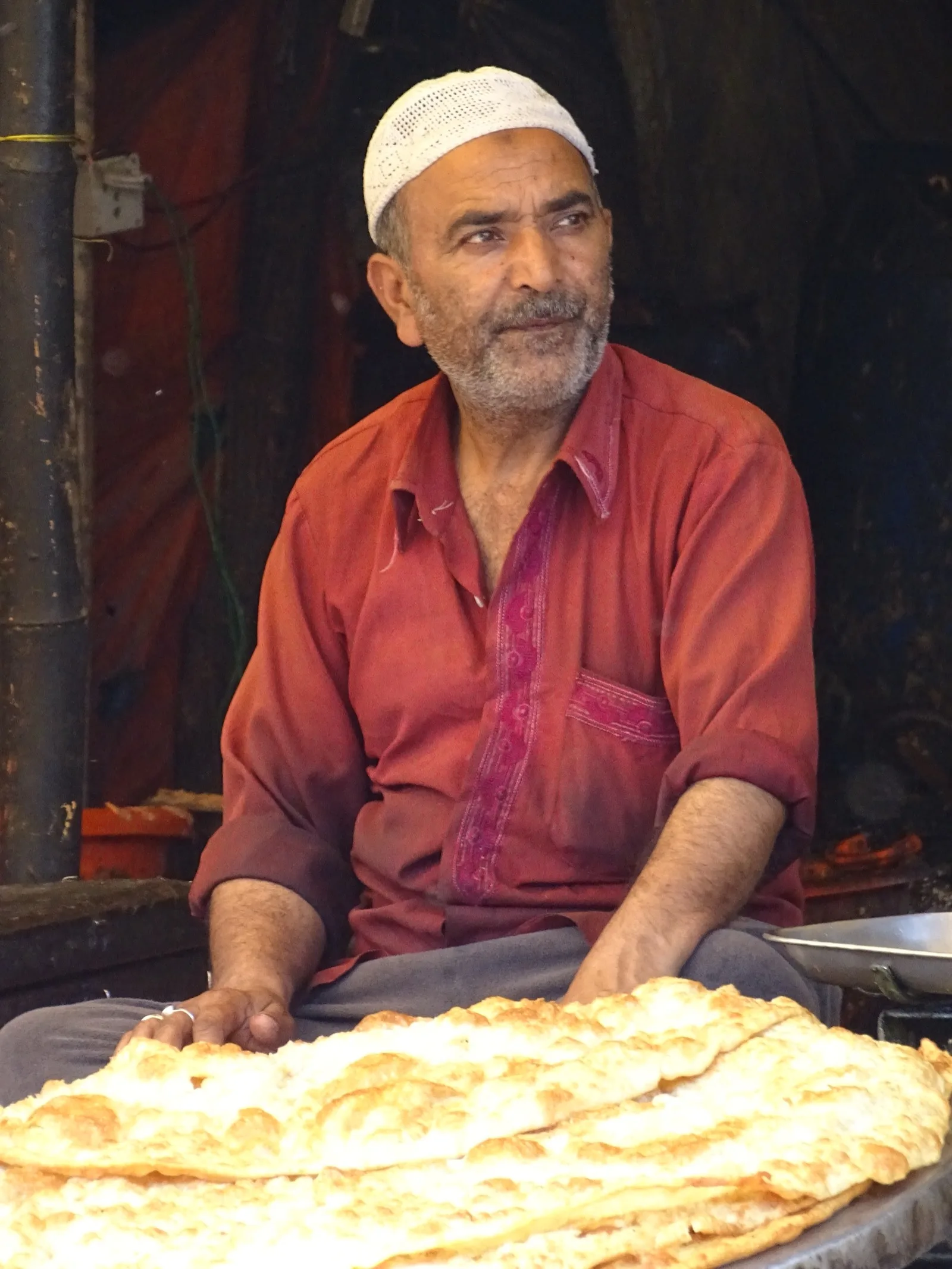 A Srinagar street food stall -- a large steel plate of mixed lentils and legumes in the foreground, a copper pot of spiced red vegetables being stirred behind, a woven basket to the side