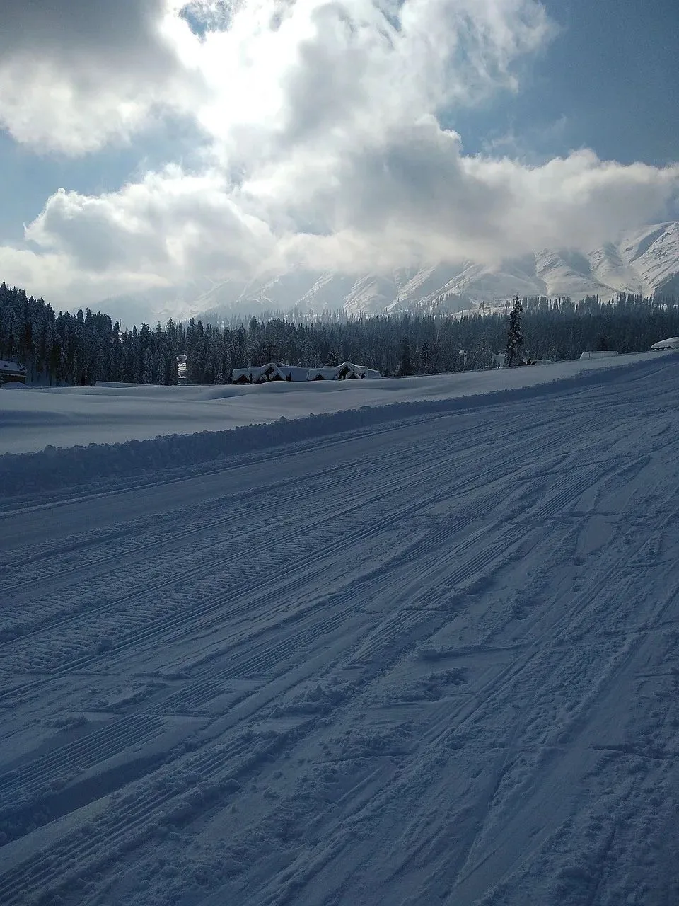 Groomed ski run in Gulmarg below misty peaks