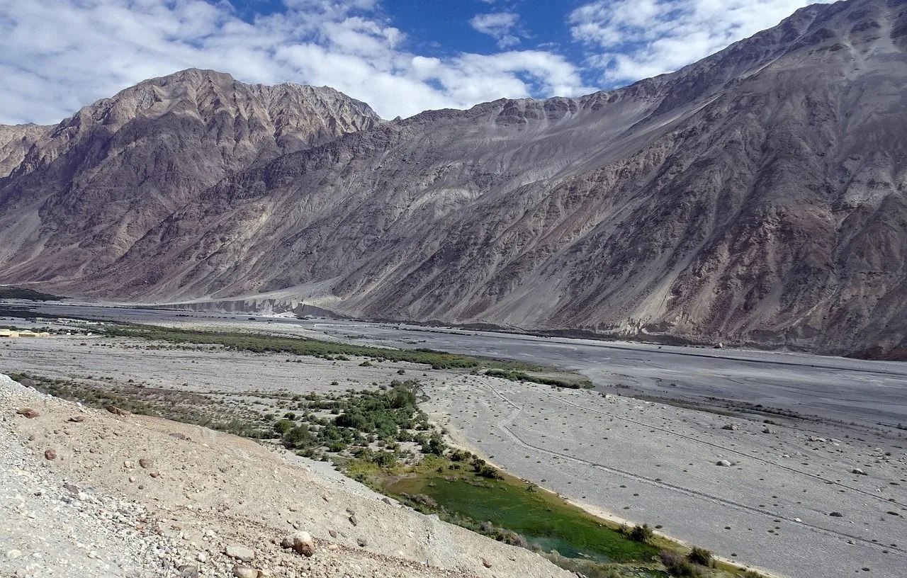 The wide braided bed of the Shyok river in Nubra Valley below grey mountains