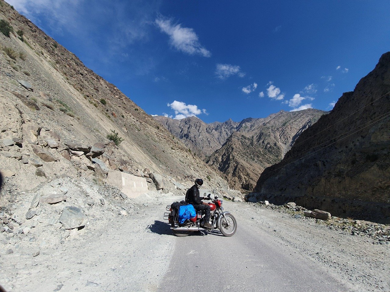 A road map view of the Kashmir valley in July -- a local cab on National Highway 1 near the Sindh river with Sonamarg visible ahead, green poplar-lined road, blue sky, the snow-capped Pir Panjal visible in the background, representing the 5-day Kashmir circuit from Srinagar to Gulmarg, Sonamarg, and Pahalgam